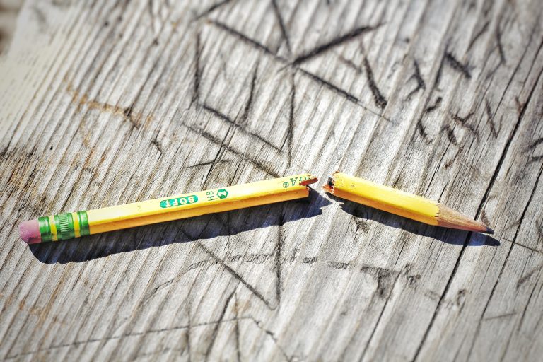 yellow broken pencil on wood background