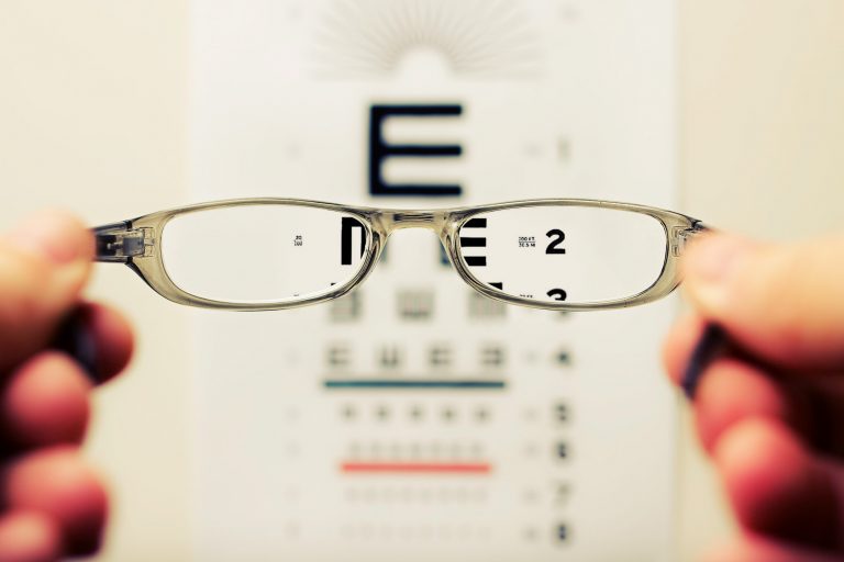 glasses-lens-in-focus-of-blurred-text-background